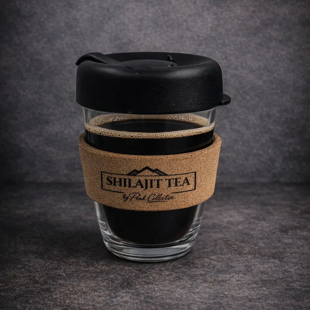 Shilajit tea cup with black lid and cork sleeve on a dark gray background