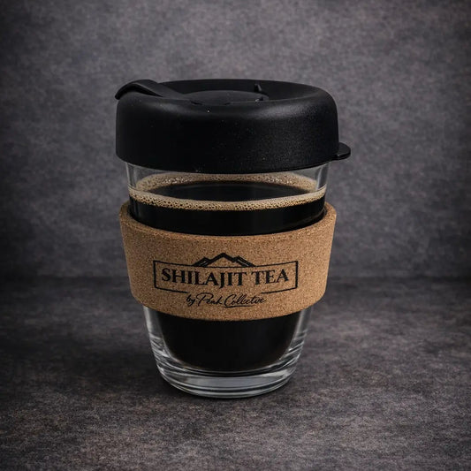 Shilajit tea cup with black lid and cork sleeve on a dark gray background