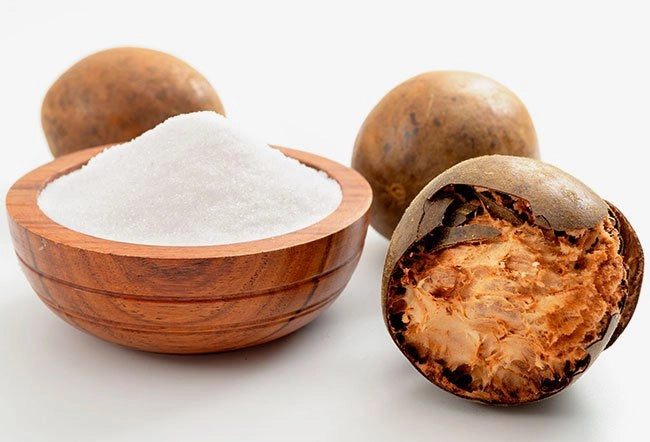 Close-up of monk fruit with monk fruit powder on white surface